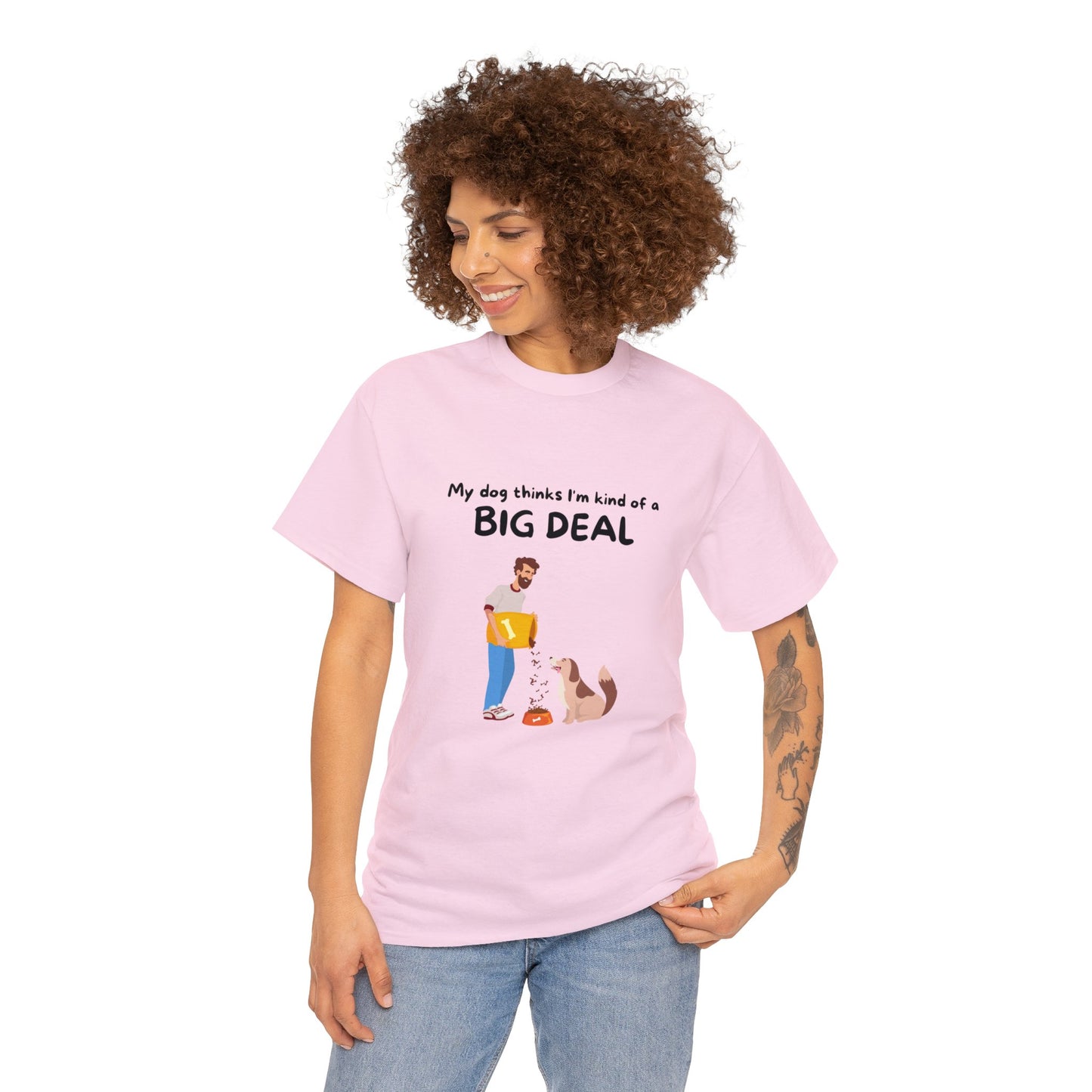 Wearing a Unisex Heavy Cotton Tee in light pink, a dog enthusiast shows off the sustainable design that reads "My Dog Thinks I'm Kind of a Big Deal," embellished with a seamless illustration of someone with their dog.