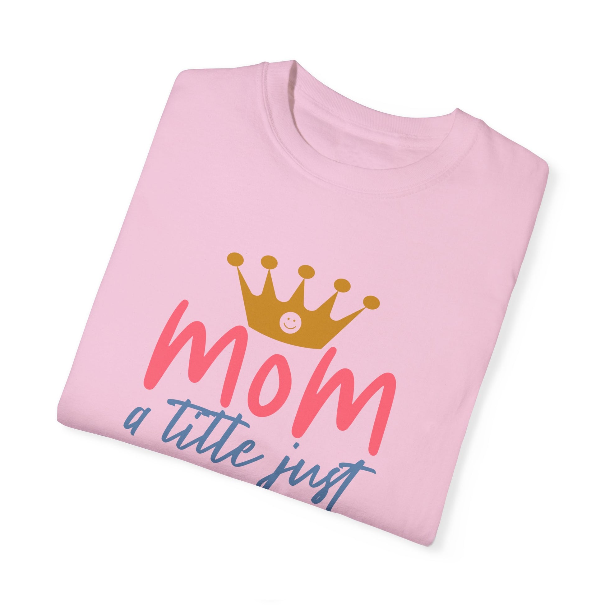 Folded pink "Stylish Comfort with Unisex Comfort Colors 1717 Garment-Dyed T-Shirt," featuring a crown design and the phrase "mom just a little above queen" in pink and blue letters, made from soft ring-spun cotton for a comfortable garment-dyed look and feel.