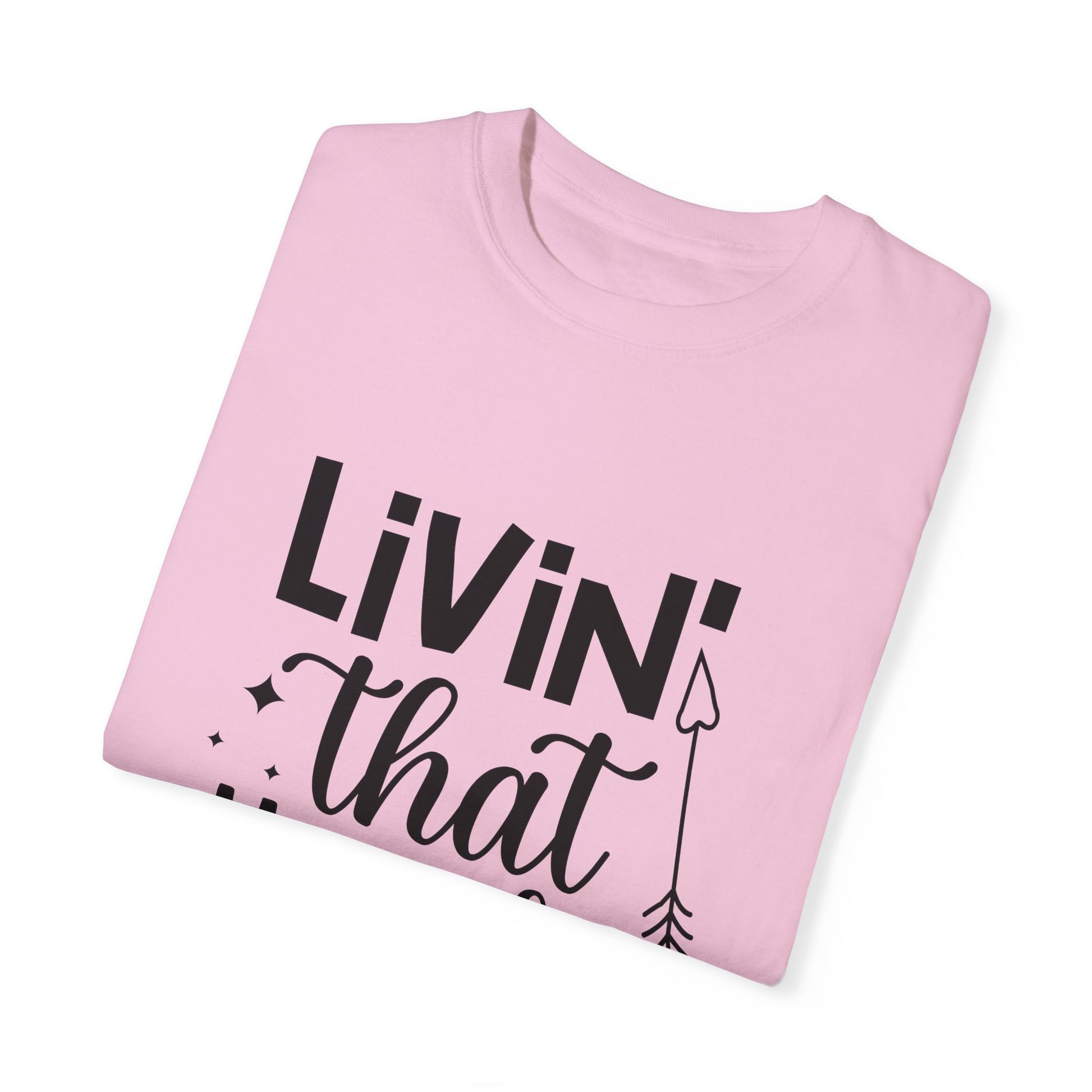 A folded pink Stylish Comfort Unisex Comfort Colors 1717 garment-dyed t-shirt, featuring black text reading "LIVIN' that" alongside a partial arrow design, made from soft ring-spun cotton for exceptional comfort.