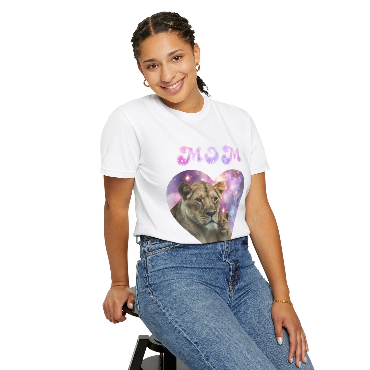 A young woman smiling, wearing a Stylish Comfort with Unisex Comfort Colors 1717 Garment-Dye- T-shirt- Heart of the Cosmos: Mom's Lioness Legacy, sitting on a black stool.