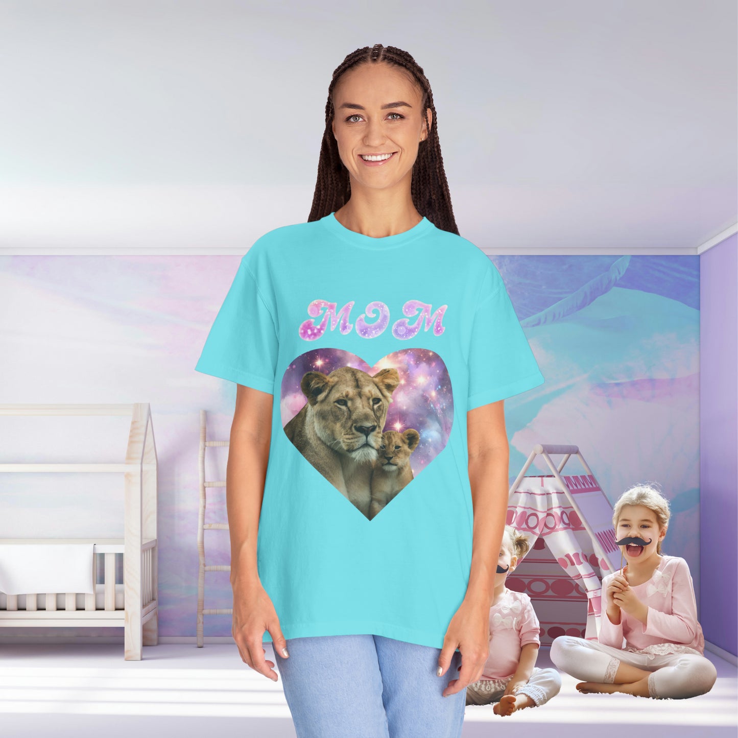 A mom in a Stylish Comfort with Unisex Comfort Colors 1717 Garment-Dye- T-shirt- Heart of the Cosmos: Mom's Lioness Legacy with a lion design stands in a colorful room, smiling, while a child plays in the background.