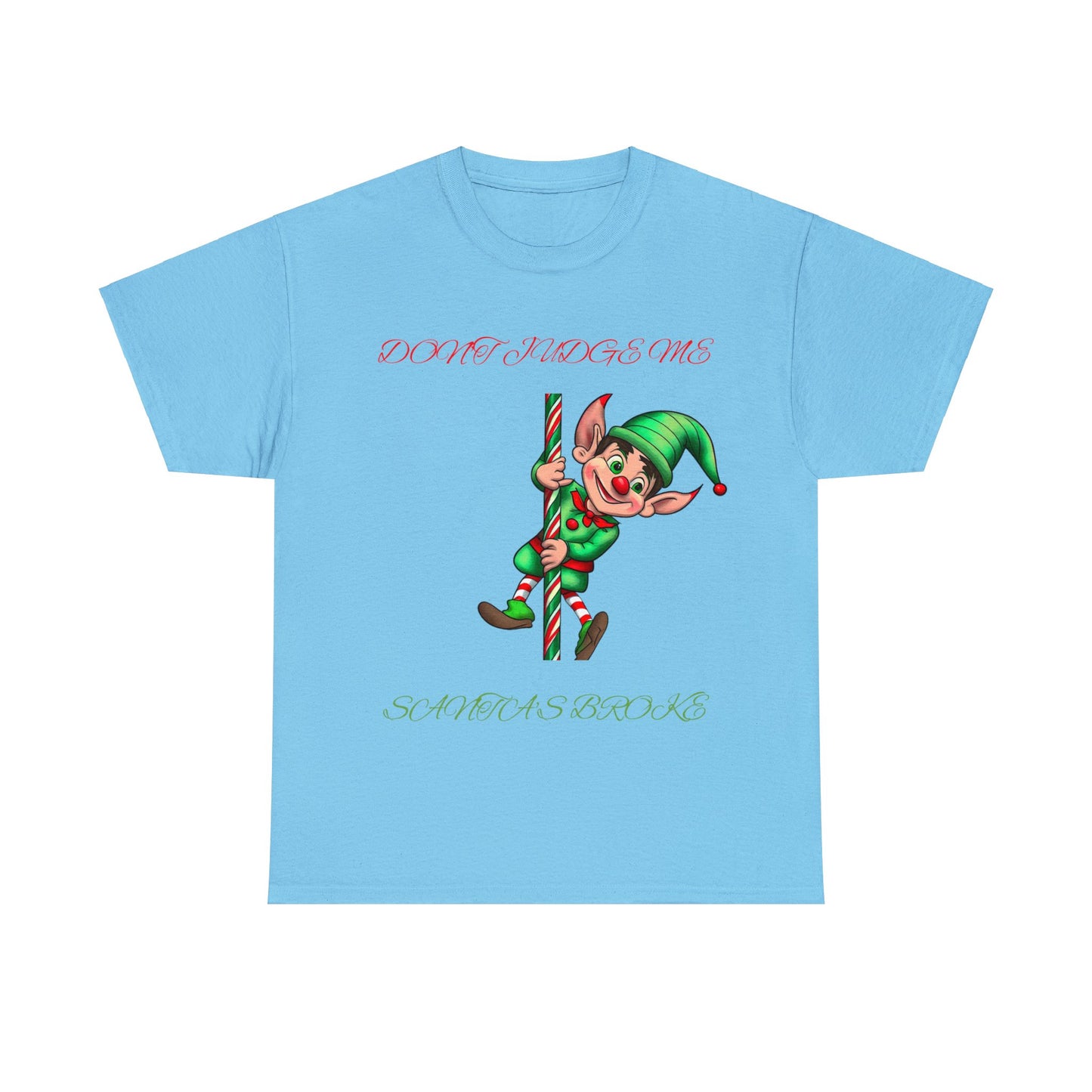 The Unisex Heavy Cotton T-shirt in classic fit showcases a playful elf perched on a candy cane with the humorous text "DON'T JUDGE ME SANTA'S BROKE." Made from 100% sustainable cotton, it's designed for both comfort and eco-friendliness.