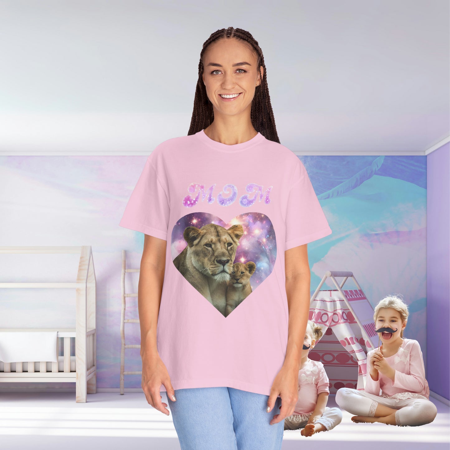 A woman in a Stylish Comfort with Unisex Comfort Colors 1717 Garment-Dye- T-shirt- Heart of the Cosmos: Mom's Lioness Legacy tee shirt, smiling in a room with children playing in the background.