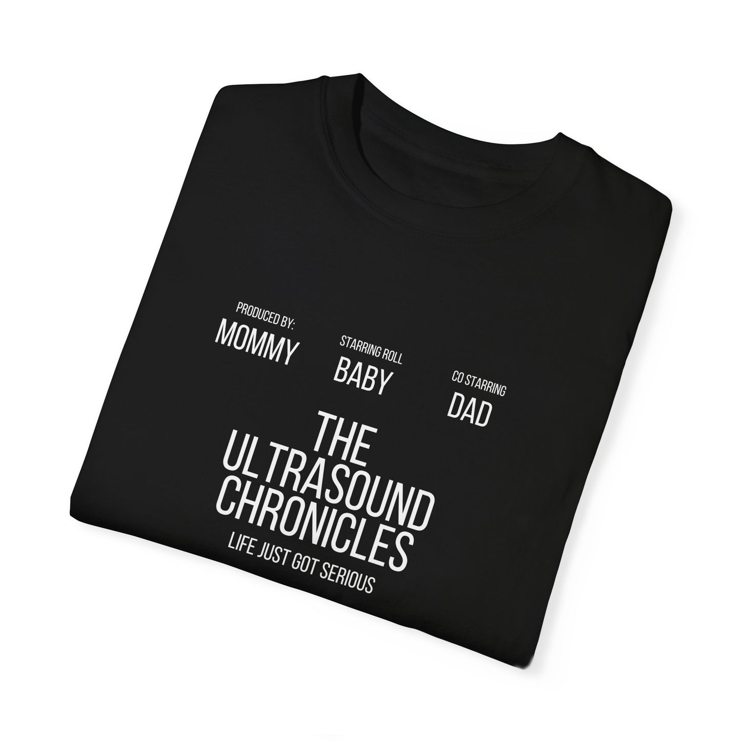 Stylish folded Unisex Comfort Colors 1717 Garment-Dye- T-shirt with white text "the ultrasound chronicles" and phrases "produced by mommy, starring baby, co-starring dad" arranged in a cinematic style.