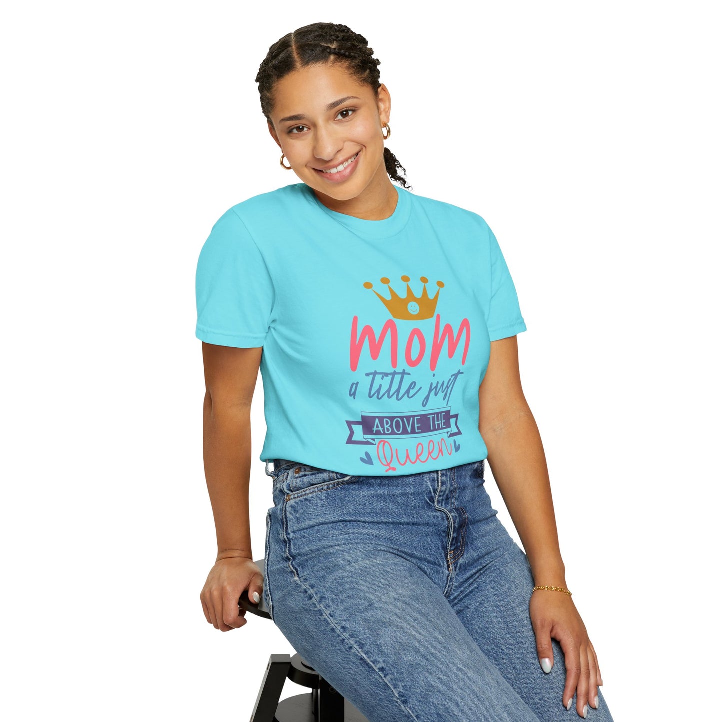 A person is sitting on a stool wearing the Stylish Comfort unisex Comfort Colors 1717 garment-dyed T-shirt in blue, featuring the text "Mom, just a little above Queen" and a crown graphic, radiating comfort and style.