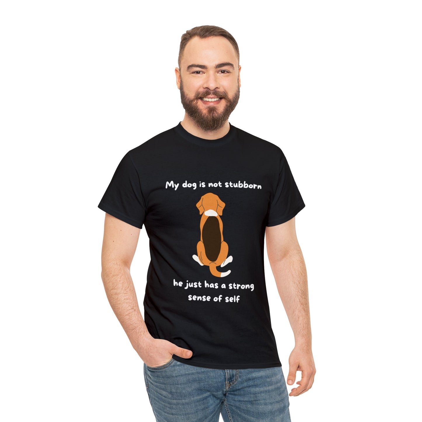 A man models the Unisex Heavy Cotton Tee - MY DOGS NOT STUBBORN- BEAGLE2, which boasts a classic fit and is made from 100% cotton. This black t-shirt features a cartoon dog alongside the text "My dog is not stubborn, he just has a strong sense of self," humorously celebrating canine independence. Crafted through sustainable production, this tee makes a charming statement about our furry friends.