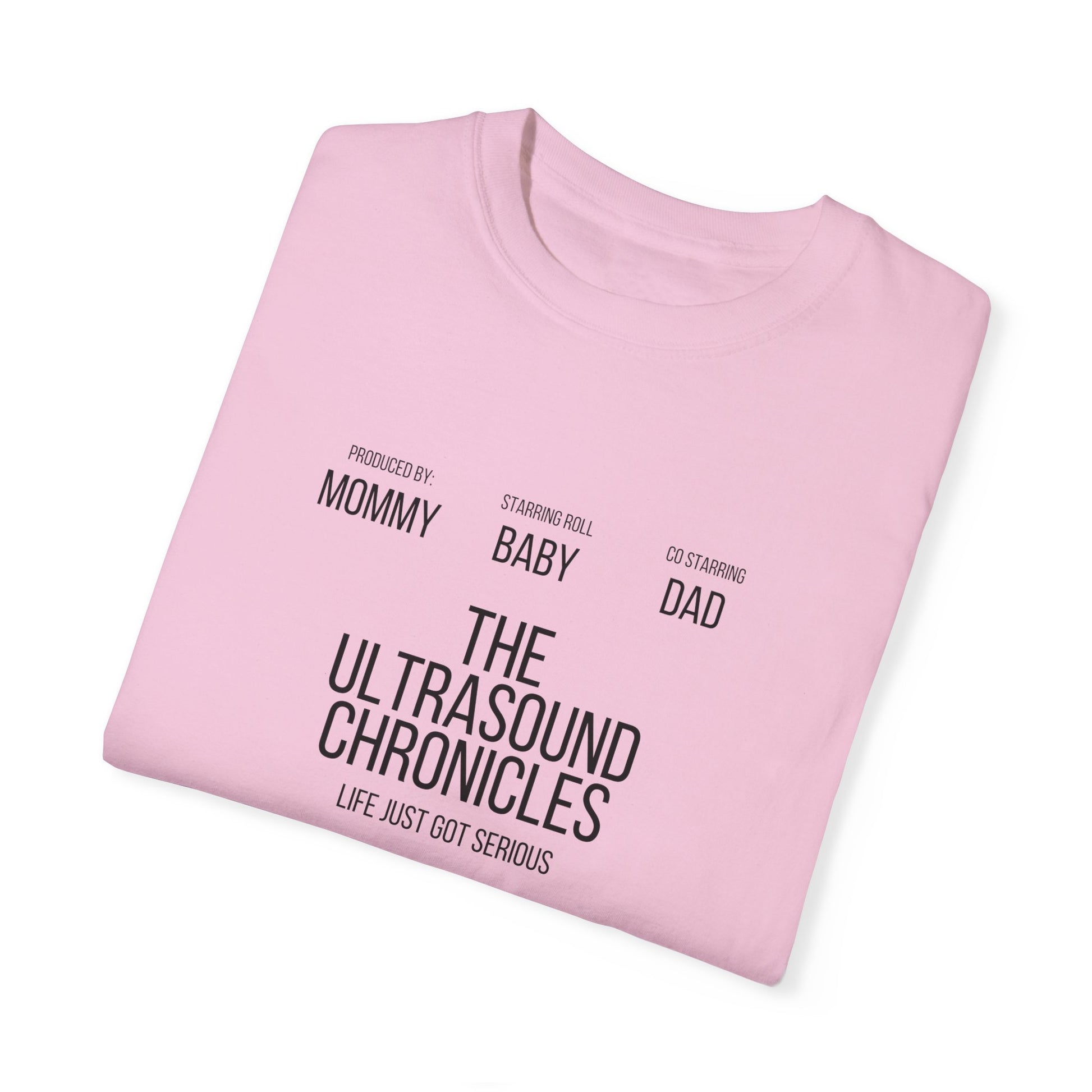 The Stylish Comfort Unisex Comfort Colors 1717 Garment-Dye T-shirt, crafted from soft ring-spun cotton in a pink hue, showcases text styled like a movie poster: "Produced by: Mommy, Starring: Baby, Co-starring: Dad. The Ultrasound Chronicles. Life Just Got Serious." Perfect for adding fun to family gatherings.