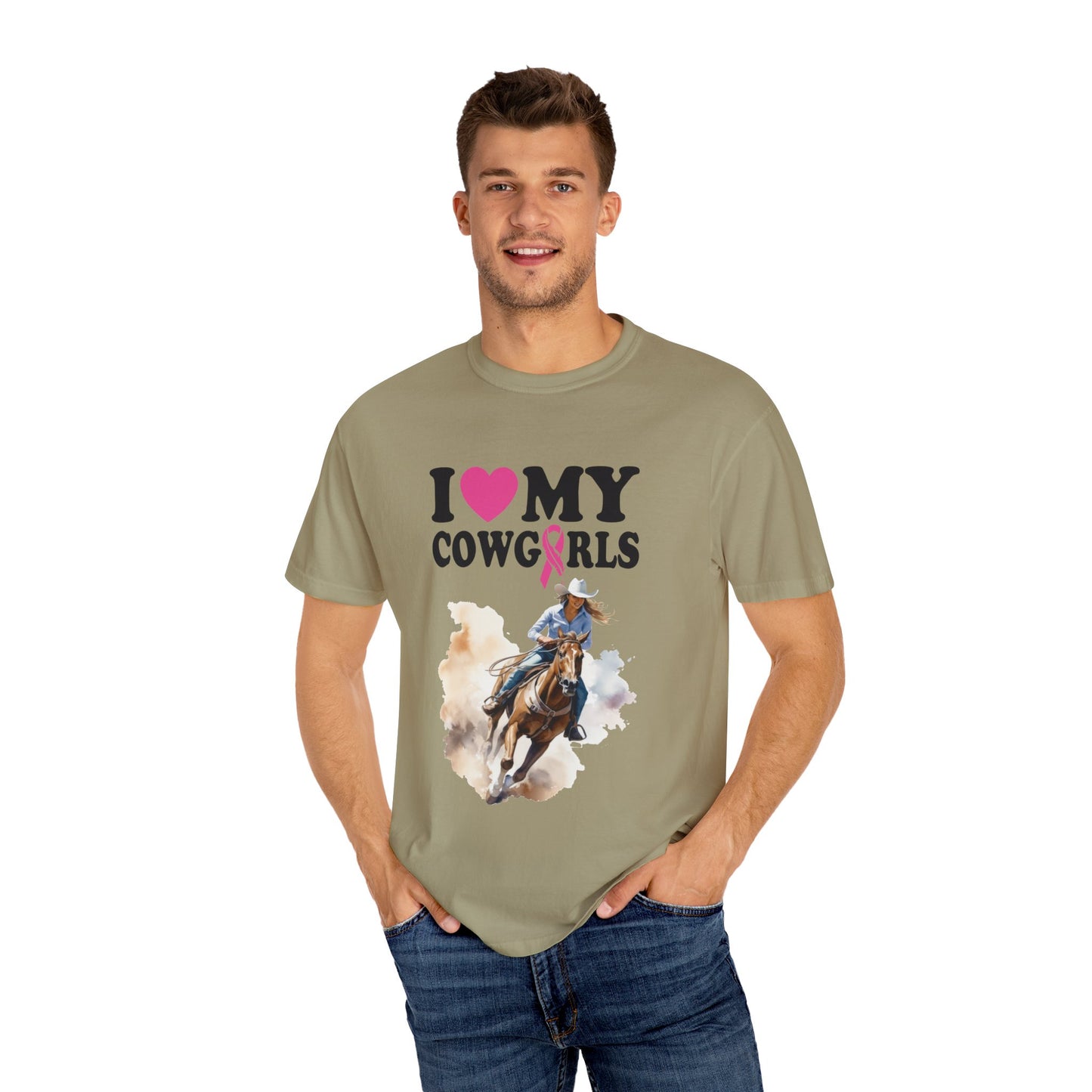 A man in a light olive, garment-dyed T-shirt with "I ♥ My Cowgirls" text and an image of a horseback rider. He has short hair, is smiling, and has his hands in his pockets, enjoying the softness of the ring-spun cotton Stylish Comfort with Unisex Comfort Colors 1717 Garment-Dyed T-Shirt- I LOVE MY COWGIRLS BREAST CANCER AWARENESS.