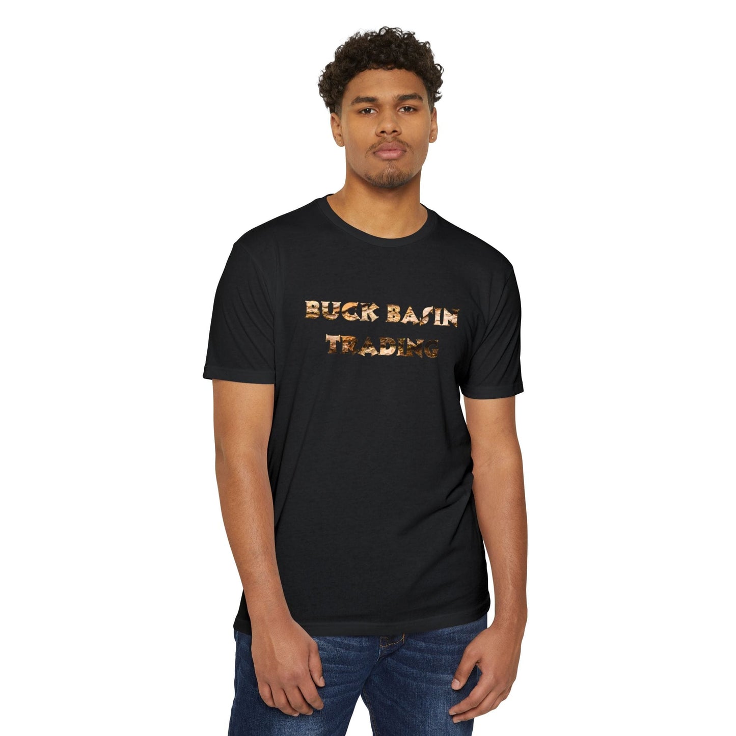 A man with short curly hair wearing a classic fit, unisex CVC jersey T-shirt with the "Buck Basin Trading Bark Logo" printed on it stands against a plain white background.