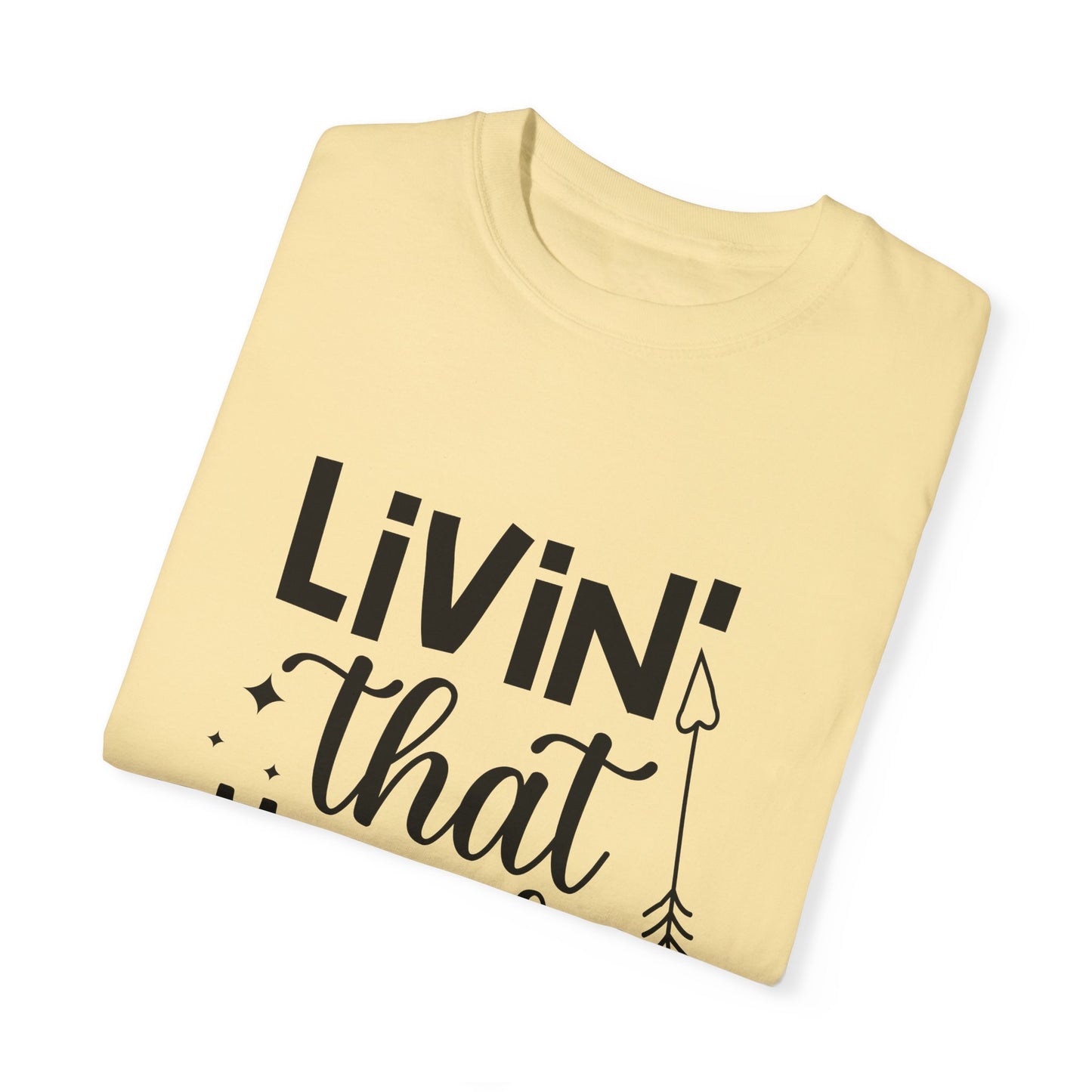 The Unisex Comfort Colors 1717 T-shirt in pale yellow, featuring black text partially visible reading "LIVIN' that," paired with a decorative arrow design, offers unmatched softness and style. Made from ring-spun cotton, this garment-dyed T-shirt embodies stylish comfort with its "Living that Mom Life" theme.