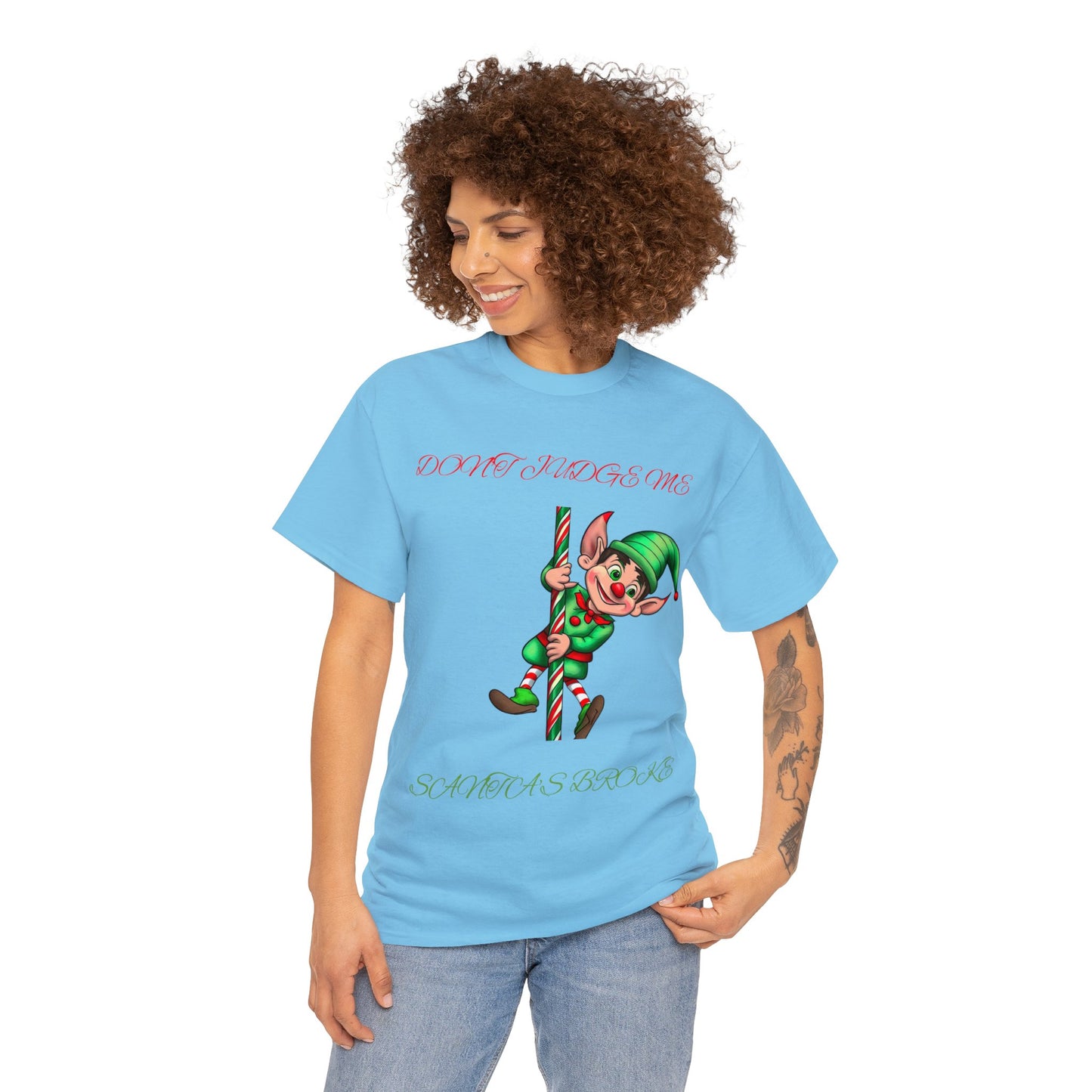 Sporting the Unisex Heavy Cotton- Don't Judge Me Elf in classic fit blue, this T-shirt is crafted from 100% cotton and showcases an illustration of an elf with a candy cane accompanied by the text, "DON’T JUDGE ME SANTA DOES IT TOO.