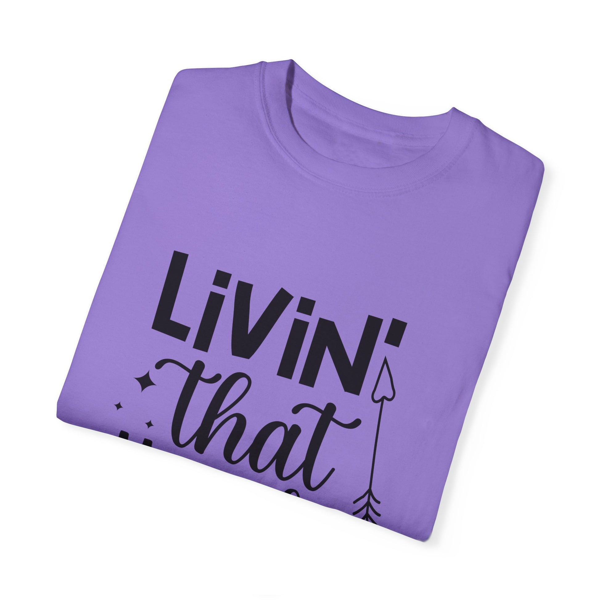 Unisex Comfort Colors 1717 Garment-Dyed T-shirt in purple, made from soft ring-spun cotton, adorned with black text saying "LIVIN' that," accented by decorative stars and an arrow.