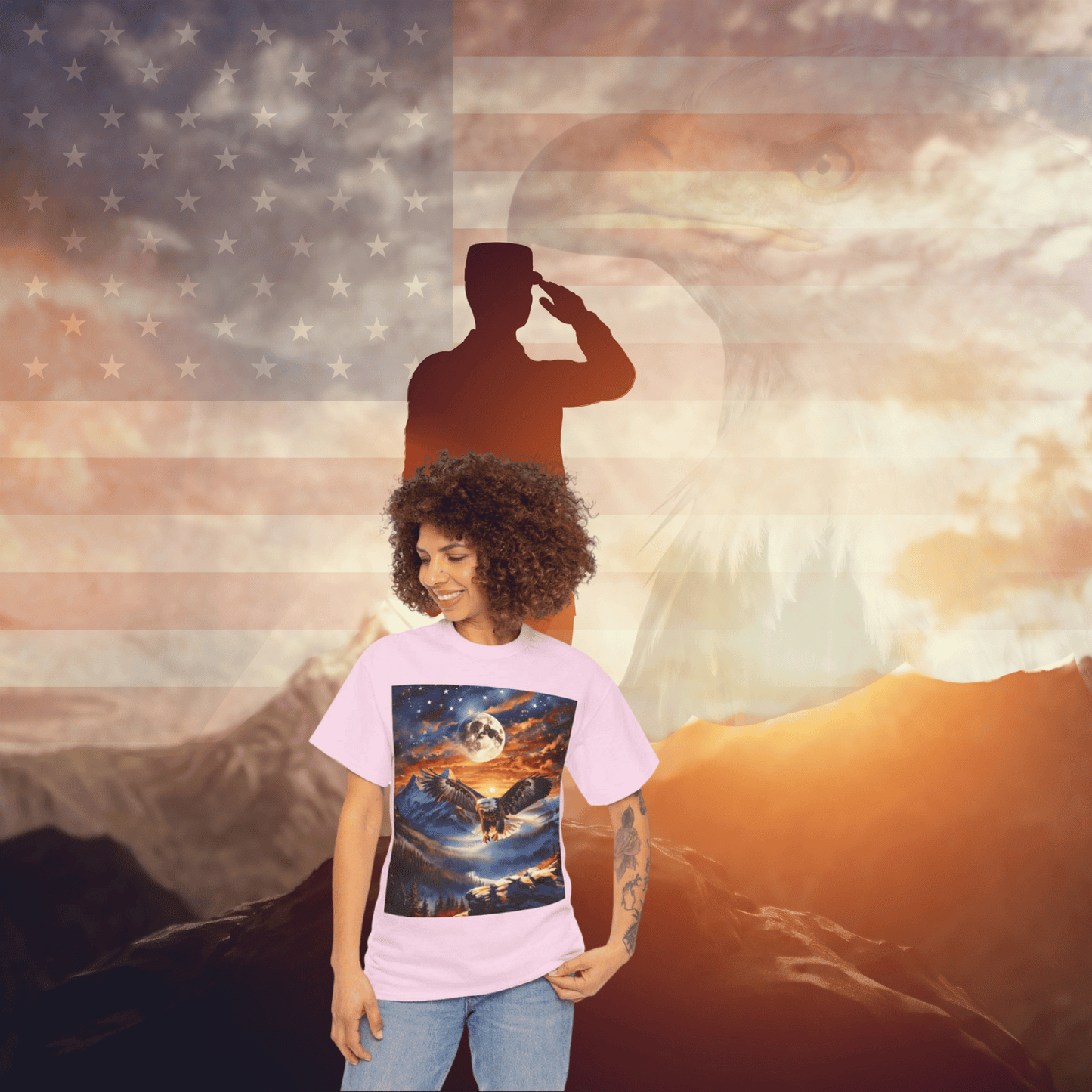 A person wearing a Unisex Heavy Cotton Tee - Stars, Stripes, and Soaring Spirit: A Bald Eagle's Tribute stands against a backdrop featuring a large American flag, a silhouetted soldier saluting, and the head of an eagle superimposed over a mountainous landscape at sunset.