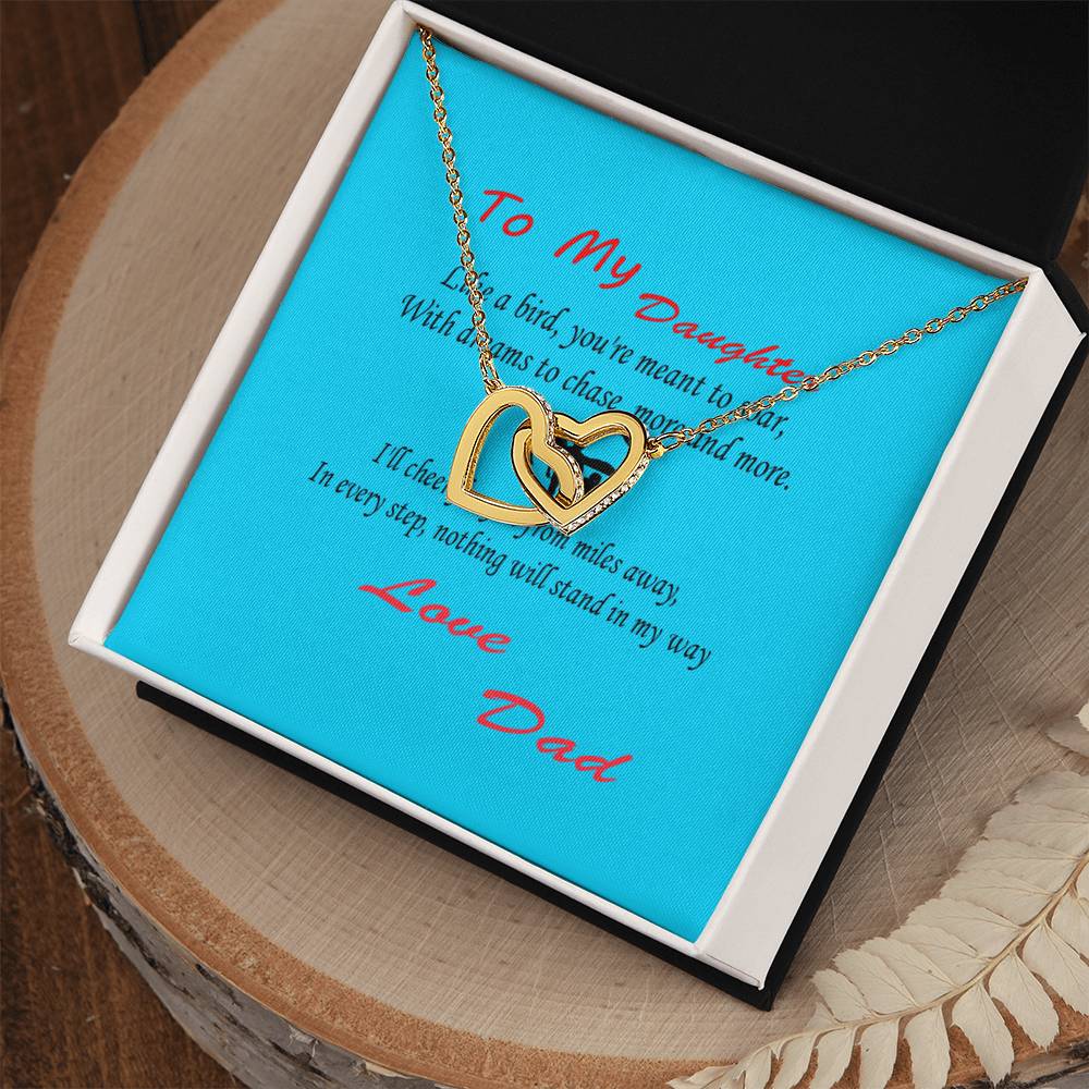 A gold Interlocking Hearts Necklace- Father Daughter Like a Bird is displayed in an open box. Inside the box, a note on a blue background carries a heartfelt message from a father to his daughter, making it an ideal Father's Day gift for dad as well.