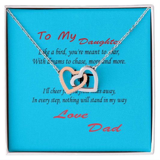 A **Interlocking Hearts Necklace- Father Daughter Like a Bird** on a blue background inside a box. The box contains a message that starts with "To My Daughter" and ends with "Love, Dad." It's the perfect gift for Father's Day from an amazing dad.