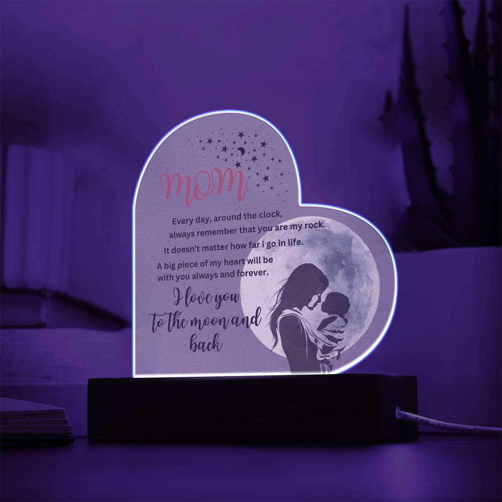 An "Mom, you are my rock, i love you to the moon" acrylic heart plaque with wooden base featuring a picture of a mom and child, illuminated for display.